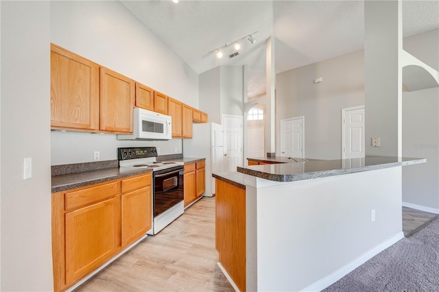 kitchen featuring high vaulted ceiling, white appliances, baseboards, dark countertops, and arched walkways