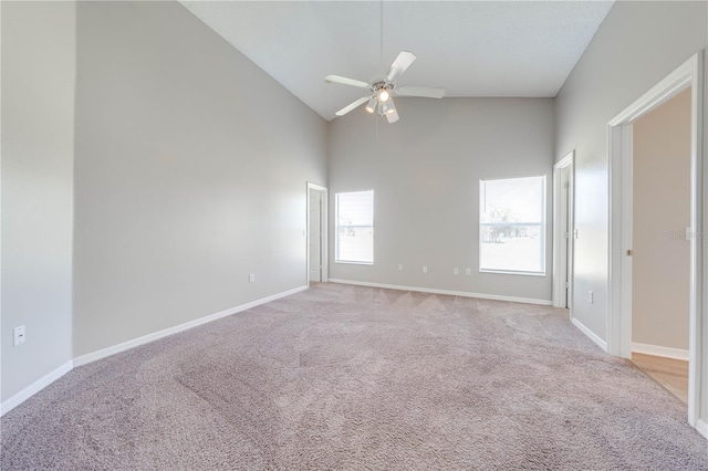spare room featuring baseboards, high vaulted ceiling, a ceiling fan, and light colored carpet