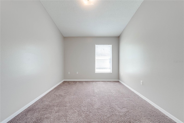 carpeted empty room with baseboards and a textured ceiling