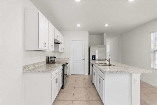 kitchen with stainless steel appliances, an island with sink, light tile patterned floors, sink, and white cabinetry