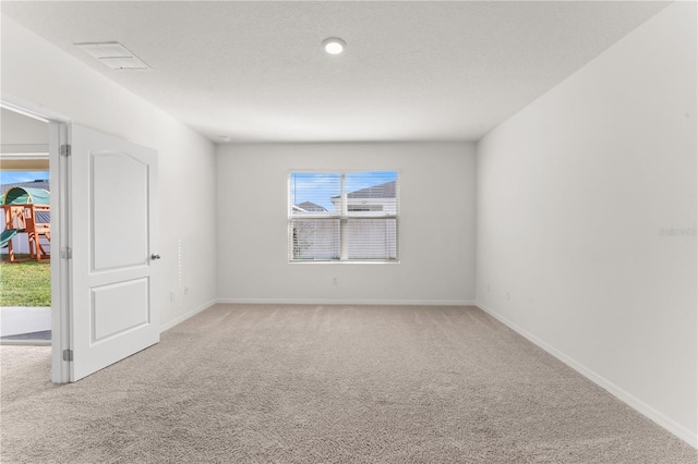 unfurnished room featuring a textured ceiling and light colored carpet