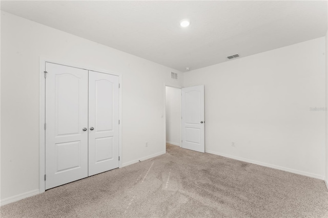 unfurnished bedroom with a closet and light colored carpet