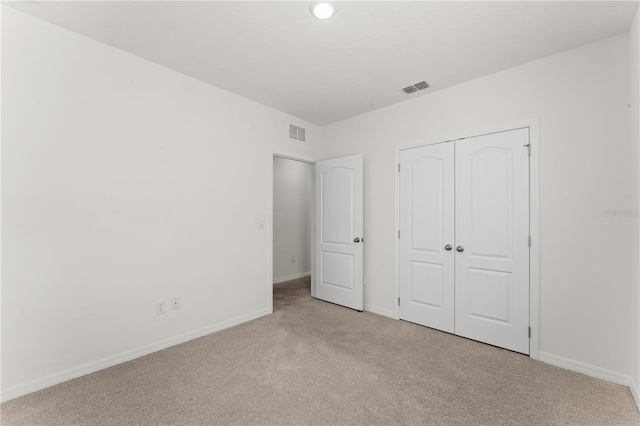 unfurnished bedroom with a closet and light colored carpet