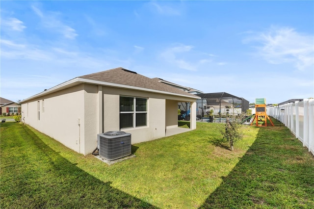 back of house featuring a playground, a yard, and central AC unit