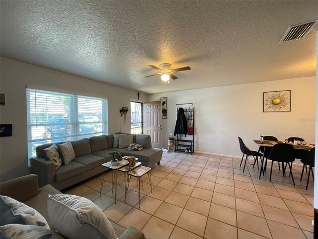 living room featuring light tile patterned floors, a textured ceiling, and ceiling fan