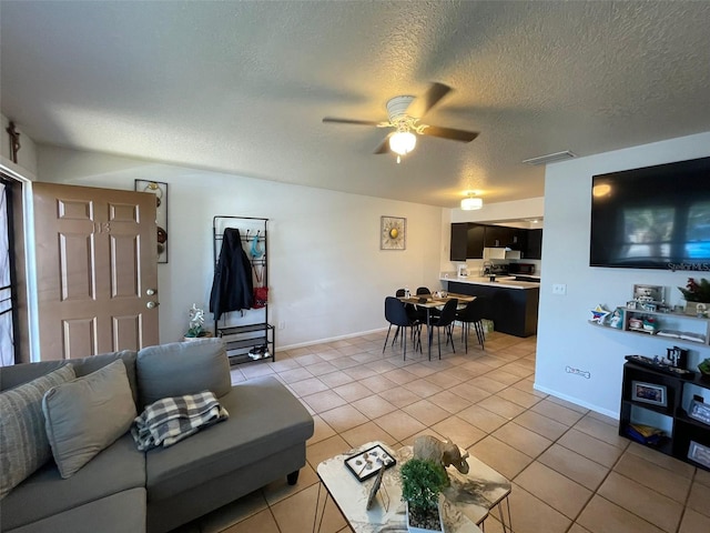 living room featuring light tile patterned floors, a textured ceiling, and ceiling fan