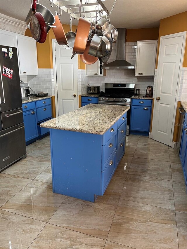 350 Corsica Ct, Kissimmee, FL 34758 - kitchen with freestanding refrigerator, wall chimney exhaust hood, tasteful backsplash, blue cabinetry, and a center island