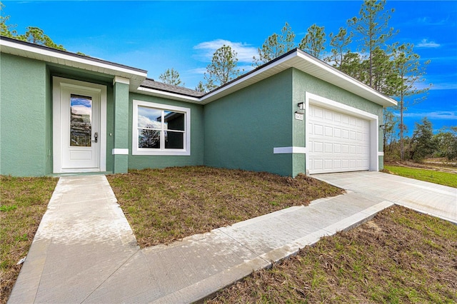 view of front of property featuring driveway, an attached garage, and stucco siding