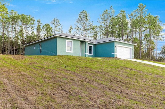 single story home with an attached garage, stucco siding, concrete driveway, and a front yard