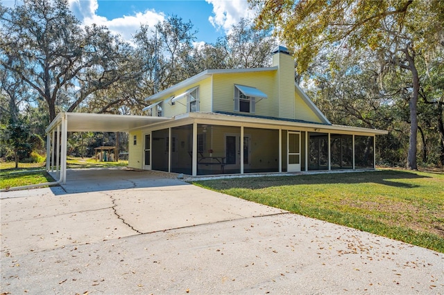 view of front of home with a front lawn, a carport, and a sunroom