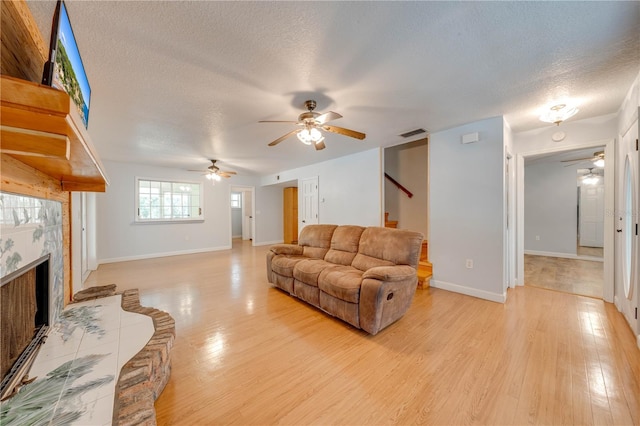 living room with a premium fireplace, a textured ceiling, and light hardwood / wood-style floors