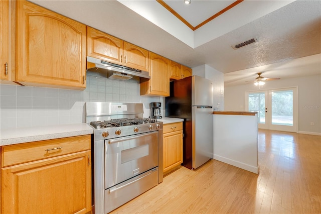 kitchen featuring crown molding, ceiling fan, stainless steel appliances, light hardwood / wood-style floors, and backsplash