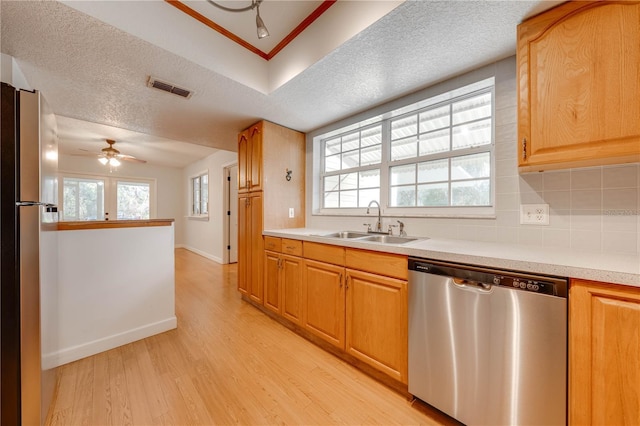 kitchen featuring sink, plenty of natural light, stainless steel appliances, tasteful backsplash, and light wood-type flooring