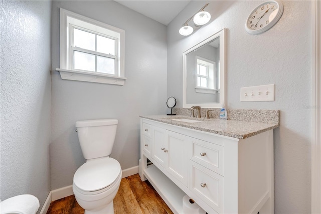 bathroom with hardwood / wood-style flooring, a healthy amount of sunlight, vanity, and toilet