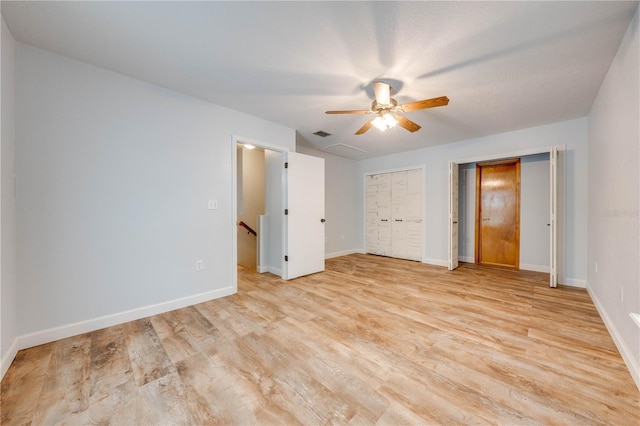 unfurnished bedroom featuring multiple closets, ceiling fan, and light hardwood / wood-style flooring