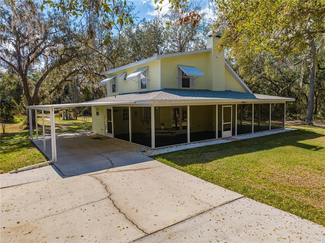 rear view of house featuring a lawn, a sunroom, and a carport