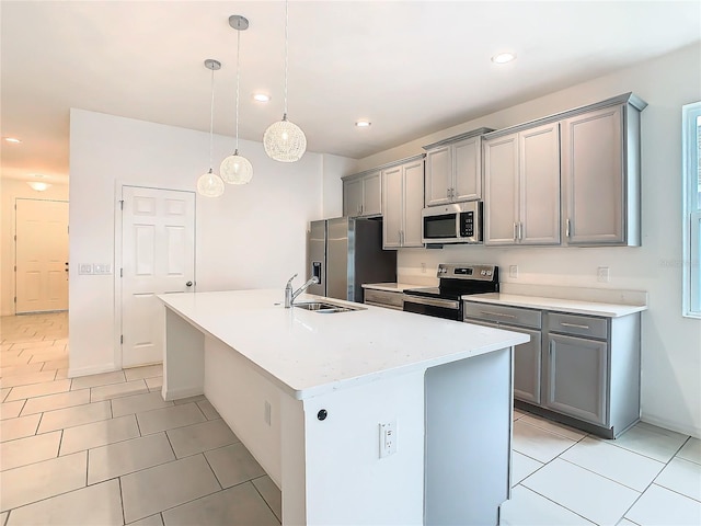 kitchen featuring gray cabinets, pendant lighting, sink, a kitchen island with sink, and stainless steel appliances