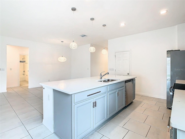 kitchen with pendant lighting, sink, light tile patterned floors, stainless steel appliances, and a center island with sink