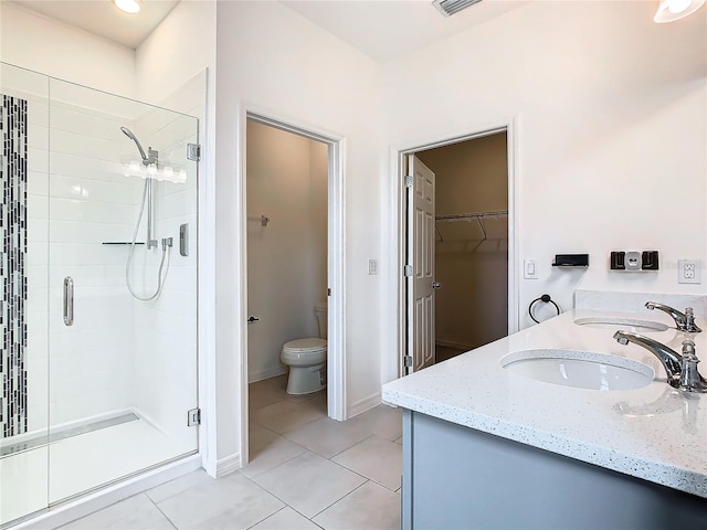 bathroom featuring tile patterned floors, toilet, a shower with shower door, and vanity