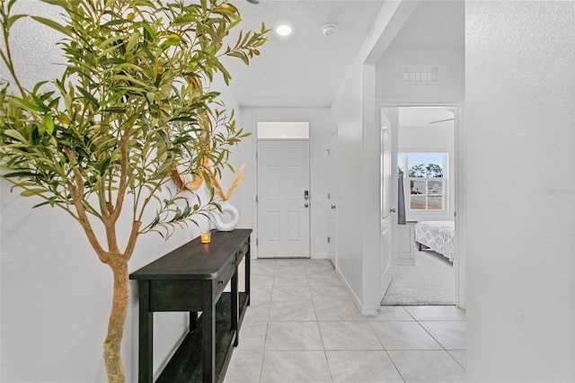 foyer entrance featuring a textured ceiling and light tile patterned floors