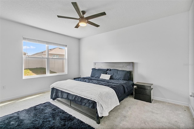 carpeted bedroom featuring ceiling fan and a textured ceiling