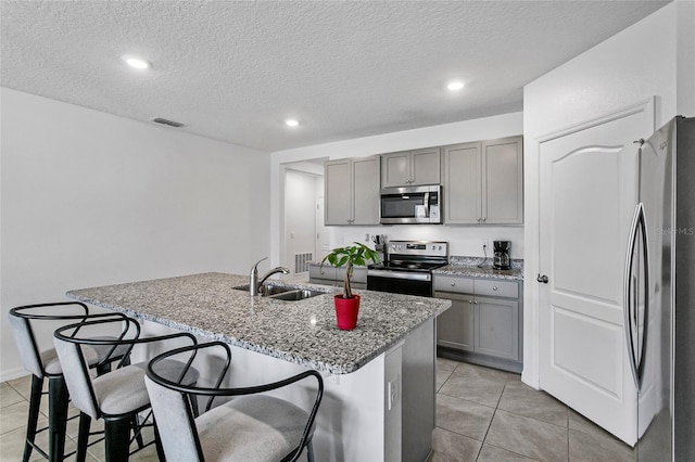 kitchen featuring stainless steel appliances, a breakfast bar area, sink, and a center island with sink