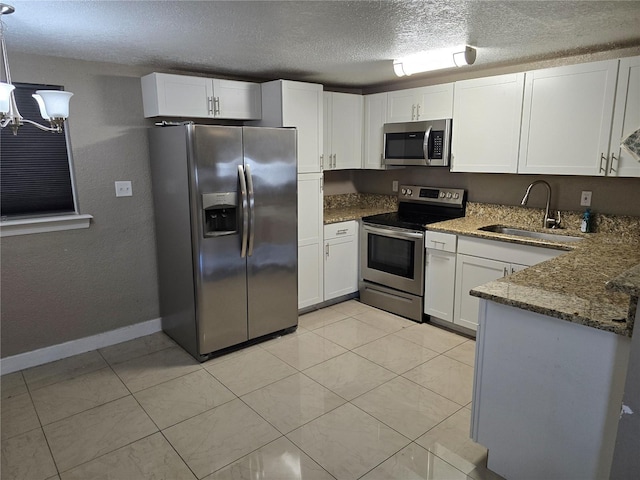 kitchen with sink, hanging light fixtures, stainless steel appliances, white cabinets, and dark stone counters