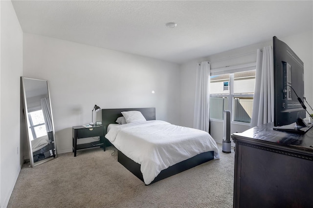 bedroom featuring light carpet, a textured ceiling, and baseboards