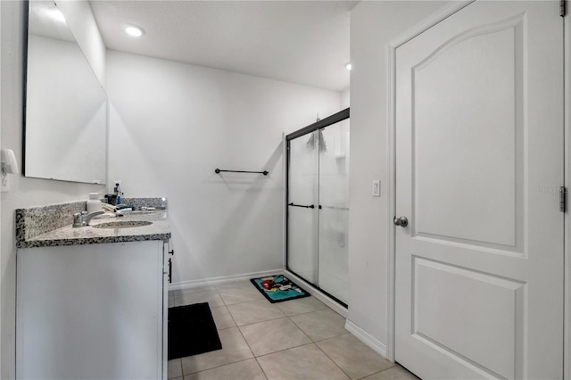 full bath with baseboards, tile patterned flooring, vanity, and a shower stall