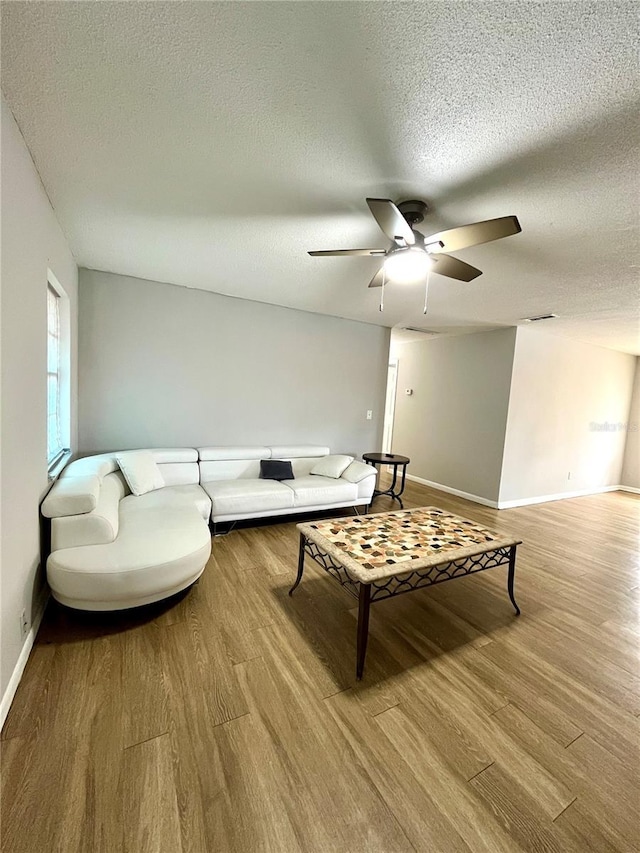 living room featuring a textured ceiling, ceiling fan, and light hardwood / wood-style flooring