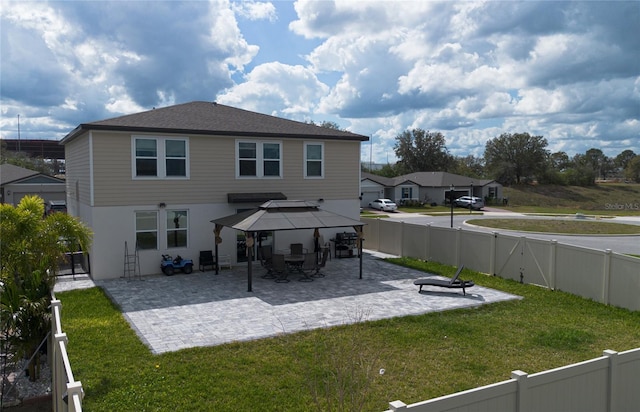 rear view of property featuring a patio, a lawn, and a gazebo