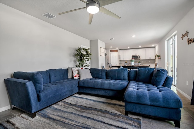 living room featuring ceiling fan and dark tile patterned flooring