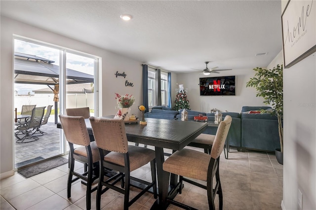 tiled dining space featuring a textured ceiling and ceiling fan