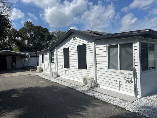 view of home's exterior with aphalt driveway, ac unit, and a detached carport