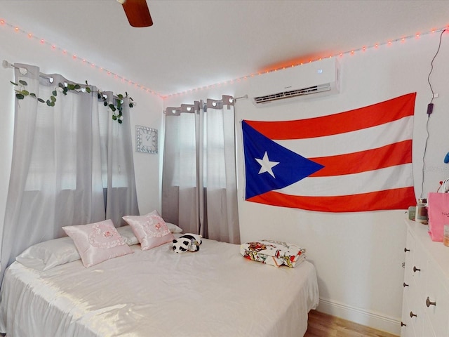 bedroom with a wall mounted air conditioner, ceiling fan, and light hardwood / wood-style flooring