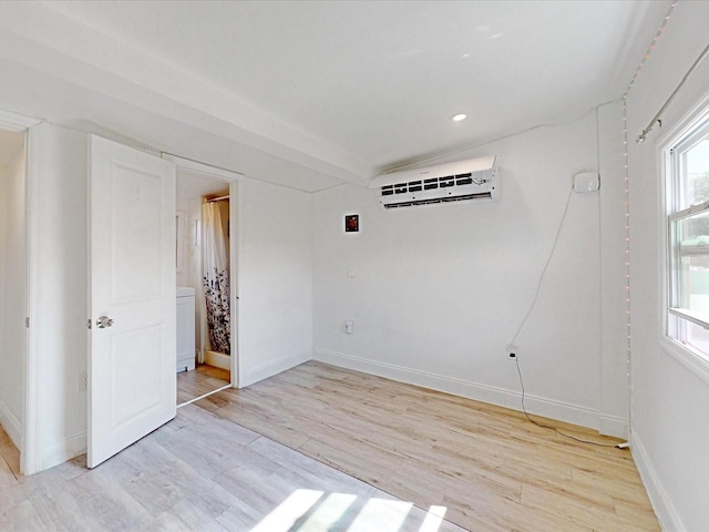 empty room featuring a wall unit AC and light hardwood / wood-style flooring