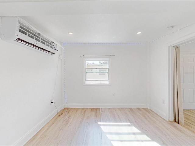 unfurnished room featuring a wall mounted air conditioner and light hardwood / wood-style flooring