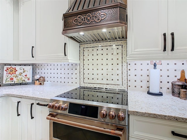 kitchen featuring white cabinetry, light stone counters, tasteful backsplash, custom range hood, and stainless steel electric stove