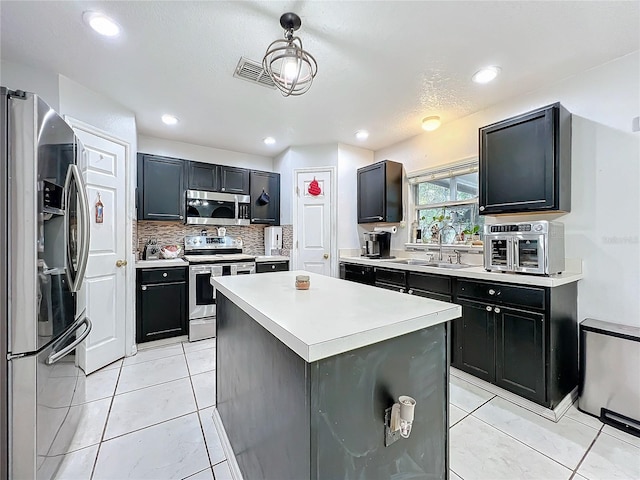 10409 Laxton St, Orlando, FL 32824 - kitchen with stainless steel appliances, a sink, dark cabinetry, tasteful backsplash, and light countertops