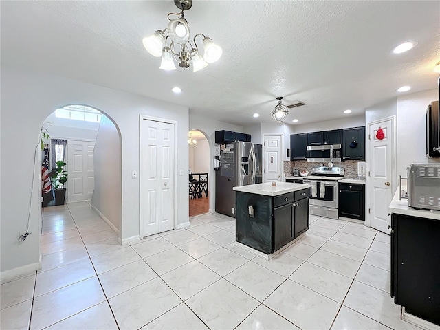 10409 Laxton St, Orlando, FL 32824 - kitchen with dark cabinetry, appliances with stainless steel finishes, arched walkways, light countertops, and decorative backsplash