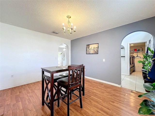 10409 Laxton St, Orlando, FL 32824 - dining room with arched walkways, a chandelier, light wood-type flooring, a textured ceiling, and baseboards