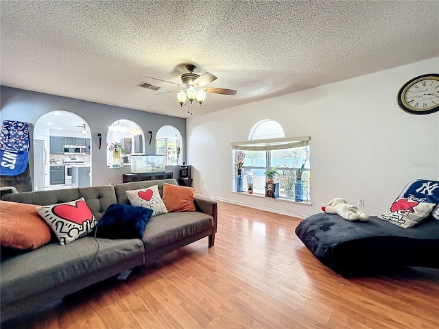10409 Laxton St, Orlando, FL 32824 - living area featuring wood finished floors, a textured ceiling, ceiling fan, and arched walkways