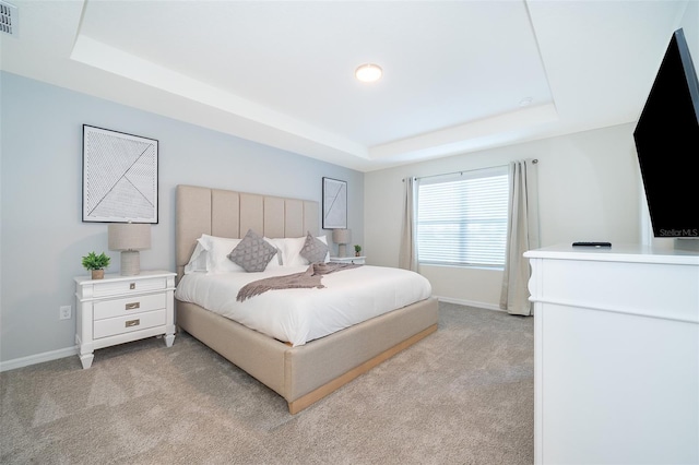 bedroom featuring light carpet and a tray ceiling