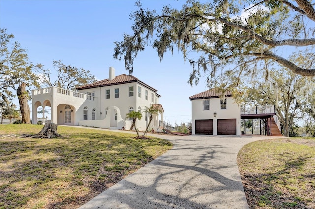 mediterranean / spanish-style house featuring a carport, a chimney, a garage, a front lawn, and stairs