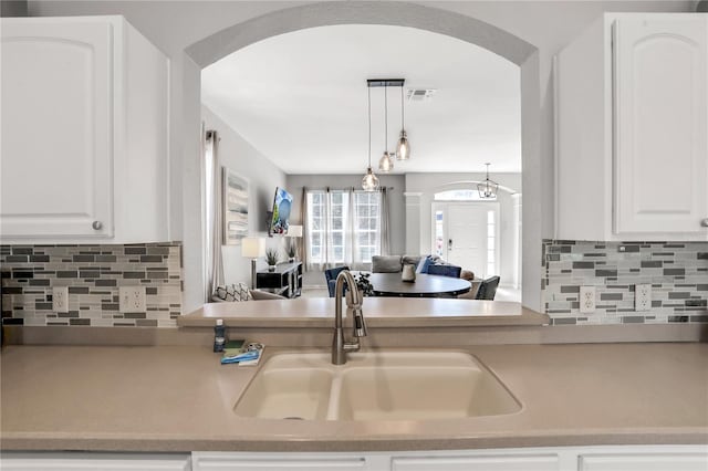 kitchen featuring sink, backsplash, hanging light fixtures, and white cabinets