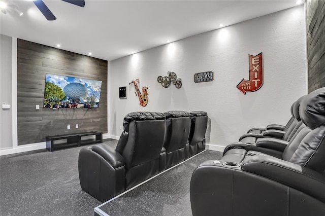 cinema room with ceiling fan and wood walls