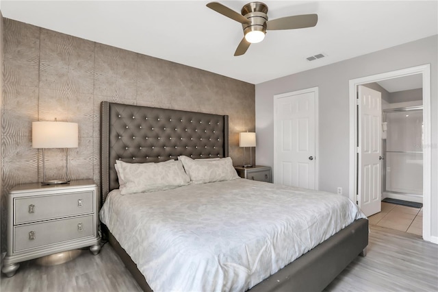 bedroom with connected bathroom, light hardwood / wood-style flooring, and ceiling fan