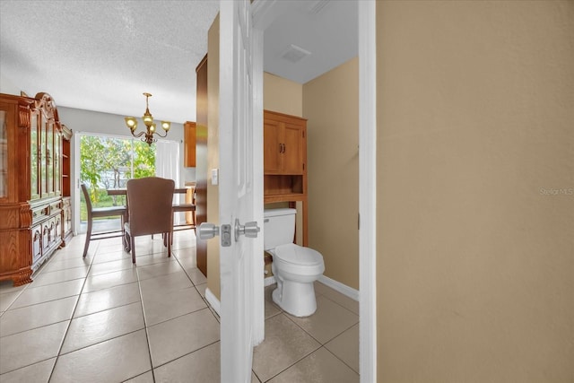 bathroom with a notable chandelier, tile patterned floors, a textured ceiling, and toilet