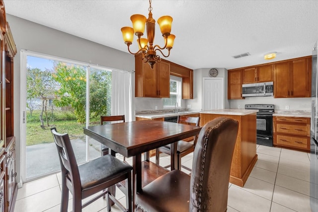 dining area with plenty of natural light, sink, light tile patterned floors, and a textured ceiling