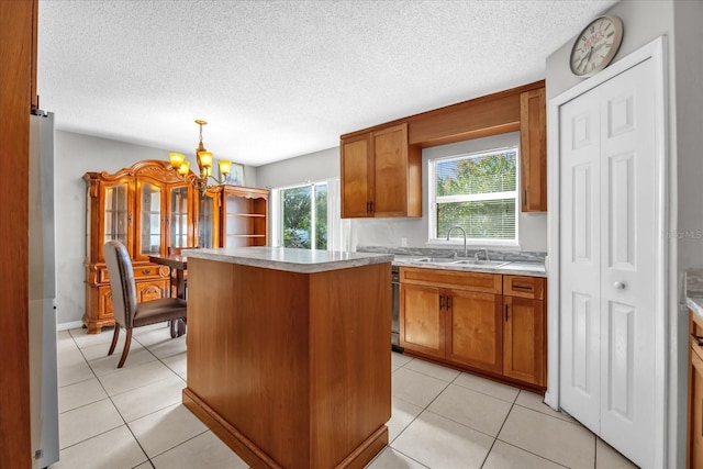 kitchen featuring a kitchen island, sink, light tile patterned floors, and decorative light fixtures